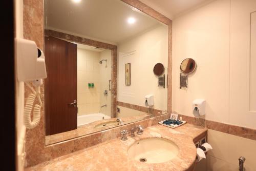 a bathroom with a sink and a large mirror at Savoy Suites Noida in Noida