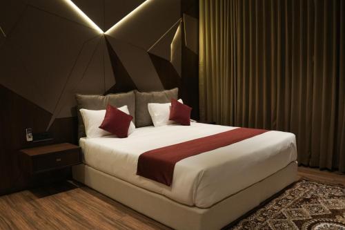a bedroom with a large white bed with red pillows at Jas Grand Homes in Cochin