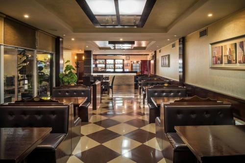 a restaurant with tables and chairs and a checkered floor at Hotel XXL in Ferizaj