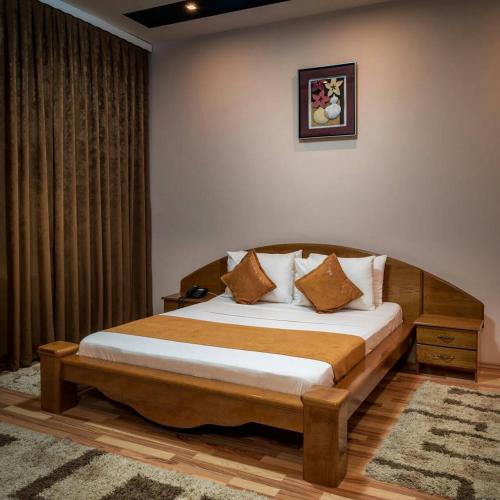 a bedroom with a wooden bed with pillows on it at Hotel XXL in Ferizaj