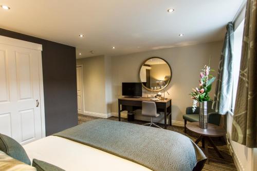a bedroom with a bed and a desk and a mirror at Woodland Grange in Leamington Spa