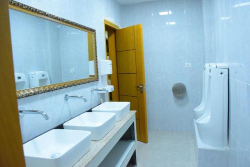 a white bathroom with two sinks and a mirror at Diamond Luxury Hotel plc in Desē
