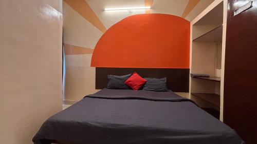 a bedroom with a bed with an orange wall at Preet Residency Homestays in Jabalpur
