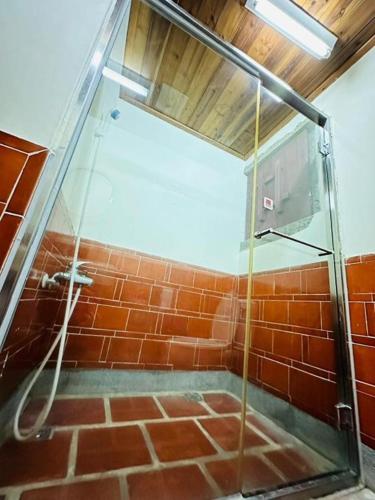a bathroom with a glass shower with red bricks at Kinmen Jinyuge Heritage B&B- Shuitou Minnan Village in Hsia-shih
