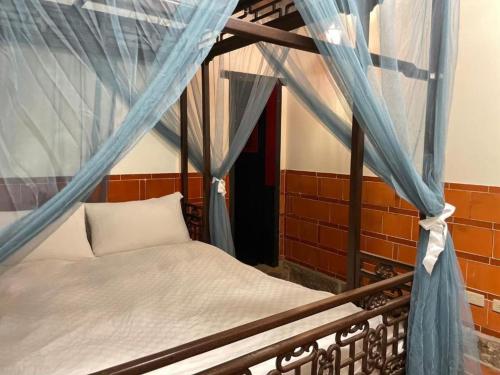 a bed in a room with a blue drapes at Kinmen Jinyuge Heritage B&B- Shuitou Minnan Village in Hsia-shih