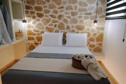a bedroom with a bed with a stone wall at Enki's Heaven Premium Apartments in Glinádhon