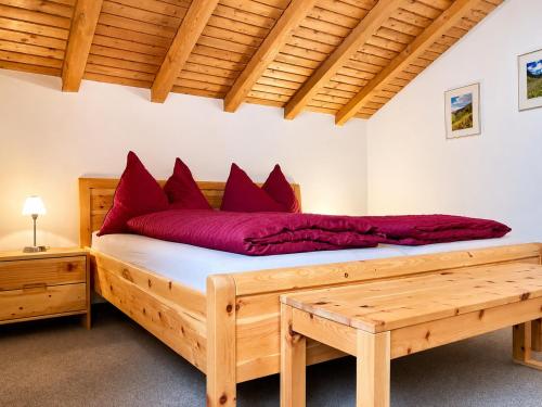 a bedroom with a large wooden bed with red pillows at Chasa Sot-Chaunt 301 in Samnaun