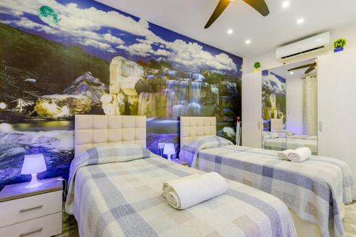 two beds in a room with a painting on the wall at Azure Apartment in Senglea