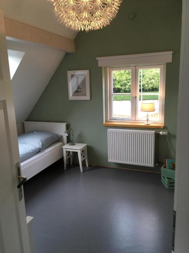 Schlafzimmer mit einem Bett, einem Fenster und einem Kronleuchter in der Unterkunft Haus Charlotte in Fehmarn