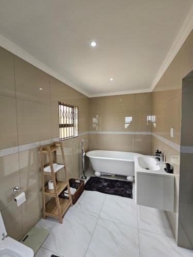 a bathroom with a bath tub and a sink at Posimuma Guesthouse Boutique in Centurion