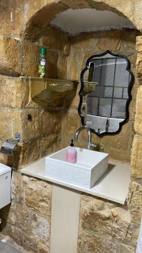 a bathroom sink with a mirror on a stone wall at Al qasr in Mashabbe Sade