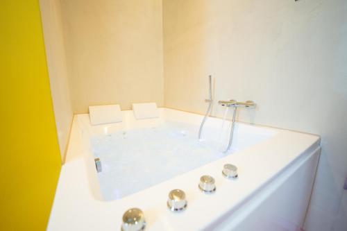 a white bath tub with a shower in a bathroom at Capsule Retro Balnéo - Sauna - Billard -Switch 2 in Limelette