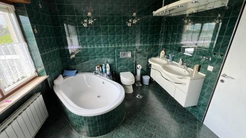 a green tiled bathroom with a tub and a sink at Apartment Kristian in Selnica ob Dravi