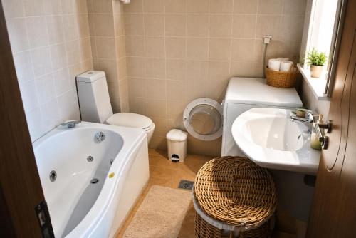 a bathroom with a tub and a toilet and a sink at 5 Stars Villas in Svoronata