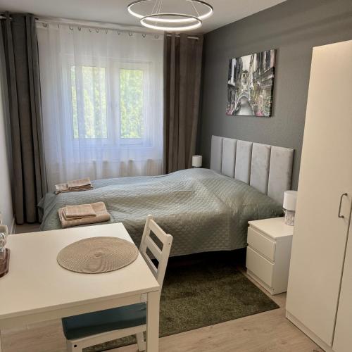 a bedroom with a bed and a table and a desk at Theo in Poznań
