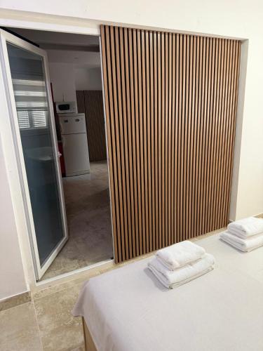 a room with a sliding glass door with towels on a bed at Apartments La Natalli in Baška