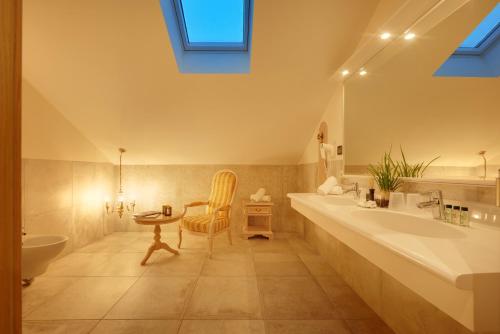 a bathroom with a tub and a sink and a chair at Historic Hotel Bircher B&B Apartments near Sterzing in Campo di Trens