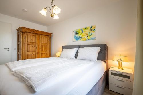 a bedroom with a large white bed and a lamp at Exklusive Ferienwohnung am Südstrand mit Meerblick & Balkon Wohnung 10 in Wilhelmshaven