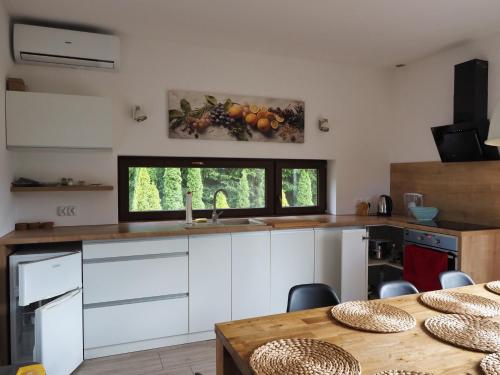 a kitchen with white cabinets and a table at Apartamenty bez barier in Rydzewo