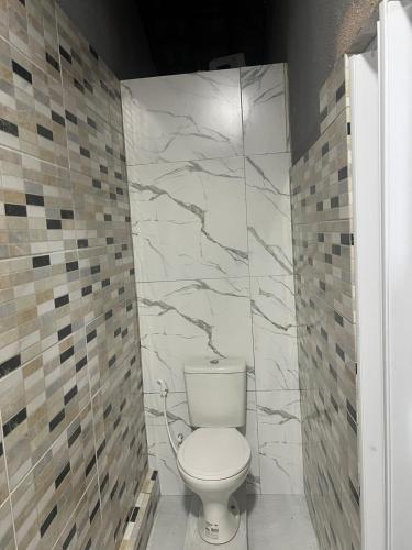 a white toilet in a bathroom with marble walls at Casa Maceió The perfect place in Maceió