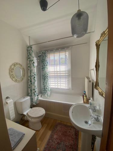a bathroom with a tub and a toilet and a sink at Glen Villa - 3 bedroom house - Stroud town centre in Stroud