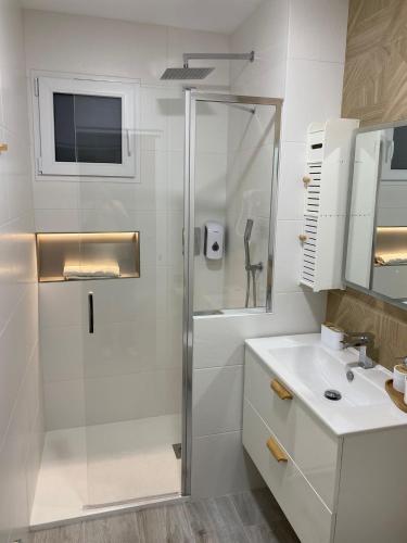 a white bathroom with a shower and a sink at AniCa III De Cine in Tomelloso