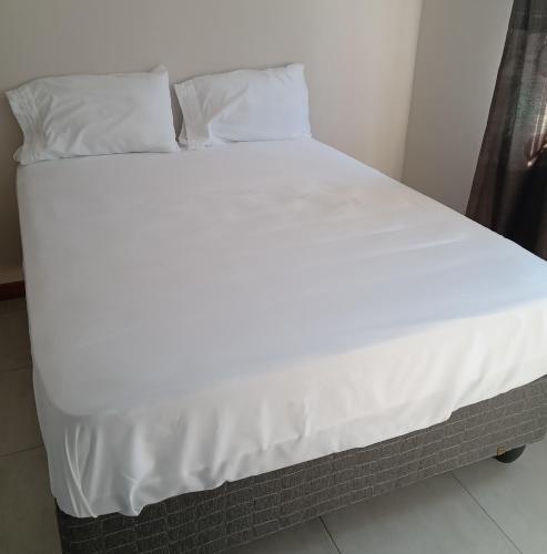 a large bed with white sheets and pillows at M's guest place Nata in Nata