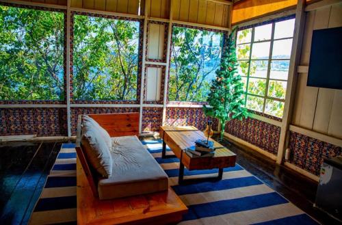 a living room with a couch and a table and windows at Santorini by Busybee Lake Cabins in Mwanza