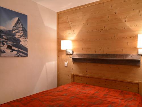 a bedroom with a wooden wall with a bed and two lights at Appartement rénové et tout confort · Au cœur de la station · Animaux admis - FR-1-181-906 in Plagne Bellecote