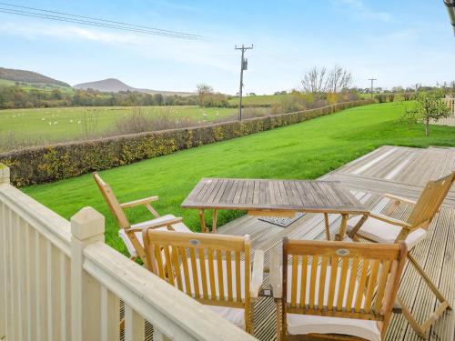 a deck with a table and chairs and a field at Beacons Cottage-Uk36406 in Bronllys