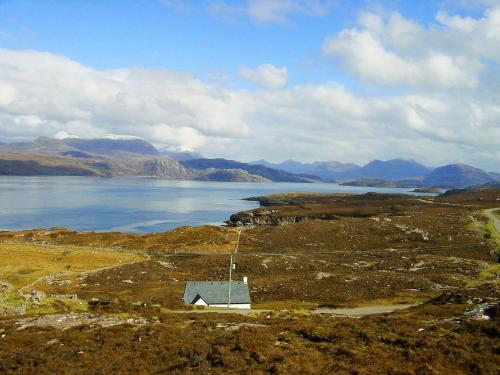 a small house on a hill next to a body of water at Fearnmore Church in Fearnmore