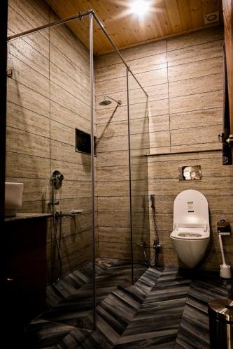 a bathroom with a toilet and a glass shower at Lofted Peaks in Pālampur