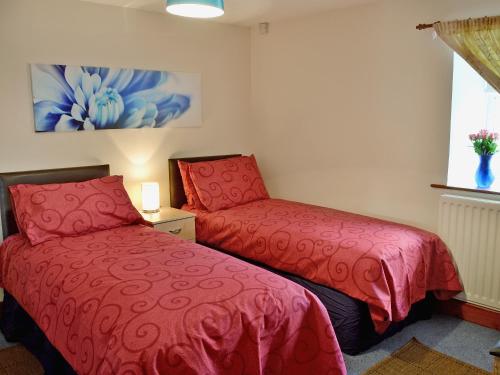 two red beds in a room with a window at Cheviot Cottage in Belford