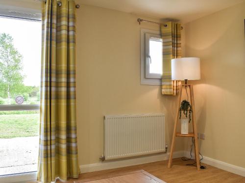 a room with a window with a radiator and a lamp at Sherwood Forest Lodge 2 in Clipstone