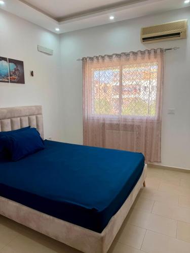 a bedroom with a blue bed and a window at Primavera Marmara Hamam sousse in Hammam Sousse