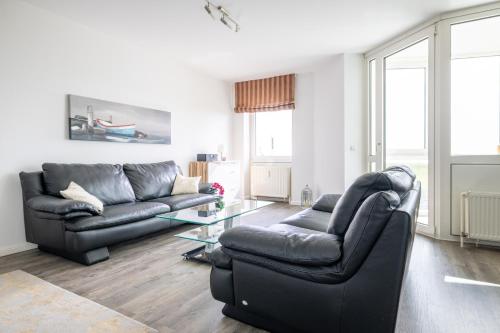 a living room with two leather couches and a glass table at Komfortable Ferienwohnung für 2 am Südstrand mit Wintergarten & Meerblick Wohnung 12 in Wilhelmshaven