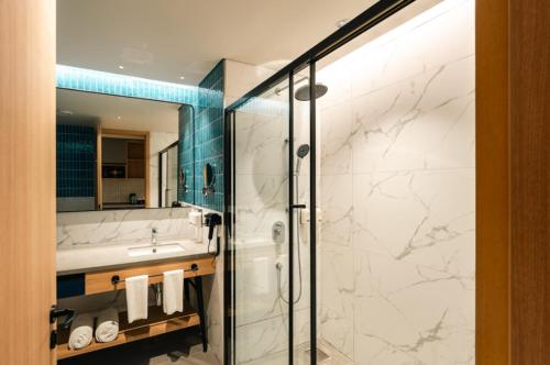 a bathroom with a shower and a sink and a mirror at The Canvas Loft-Manyata Tech Park-Orchid Parc in Bangalore