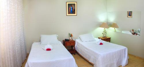 a bedroom with two beds with white sheets and red roses on them at Hotel Princess in Ica