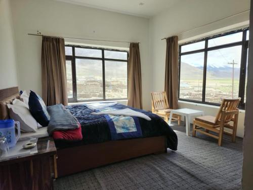 a bedroom with a bed and a desk and windows at Zim Retreat Tsokar in Pongunagu