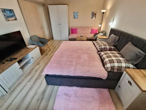 a bedroom with a large bed with a pink blanket at Móra Corner Apartman Mezőkövesd in Mezőkövesd