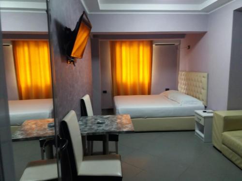 a hotel room with two beds and a table and chairs at Vila Ali Demi in Tirana