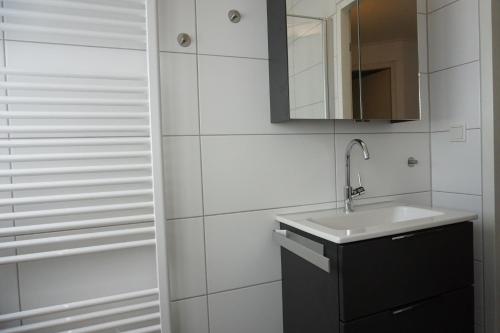 a white bathroom with a sink and a mirror at Kustverhuur, Park Scheldeveste Zwin 065 in Breskens