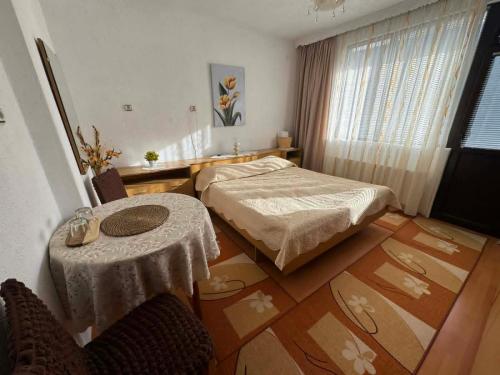 a bedroom with a bed and a table and a window at Къща за гости Здравец  in Trigrad