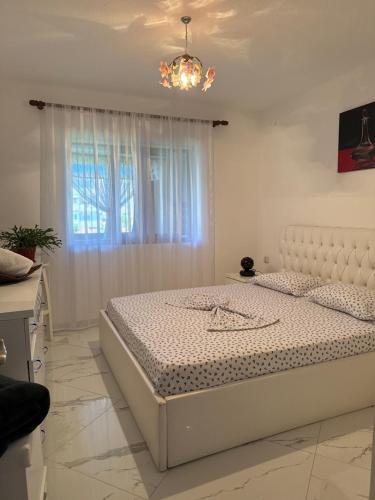 a white bedroom with a bed and a window at JEA House in Pogradec