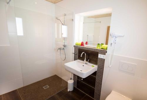 a white bathroom with a sink and a shower at ROOM'Z zimmeraufzeit in Forstinning