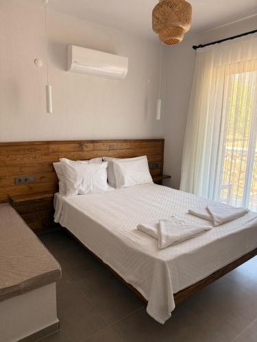 a bedroom with a bed with white sheets and a window at Petra Evleri in Örencik
