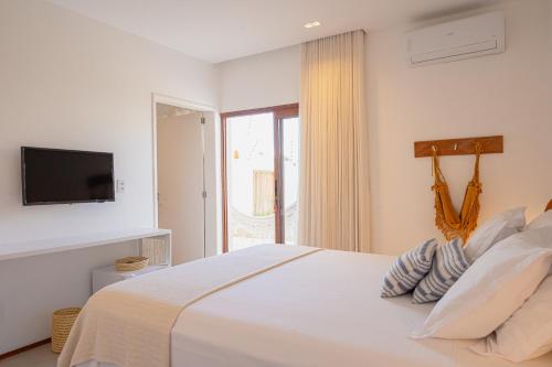 a bedroom with a white bed with a tv on the wall at Casa Aia - Hospedagem de Charme na Atalaia in Aracaju