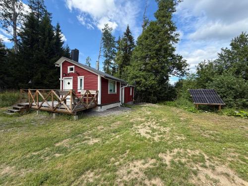 a red house with a solar panel next to a yard at The Hermits Hut in Österby