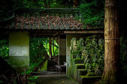 an entrance to a garden with a bunch of statues at Okamotoya in Beppu