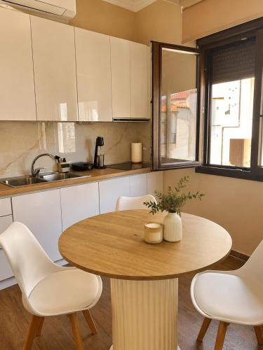 a kitchen with a wooden table and white chairs at Bright and central apartment in Siátista